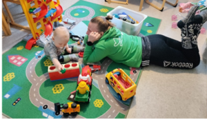 Ohjaaja leikkii lapsen kanssa liikennematolla
